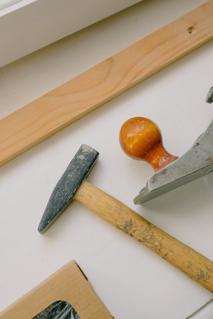 Collection of carpentry tools including hammer and jack plane on a wooden surface.